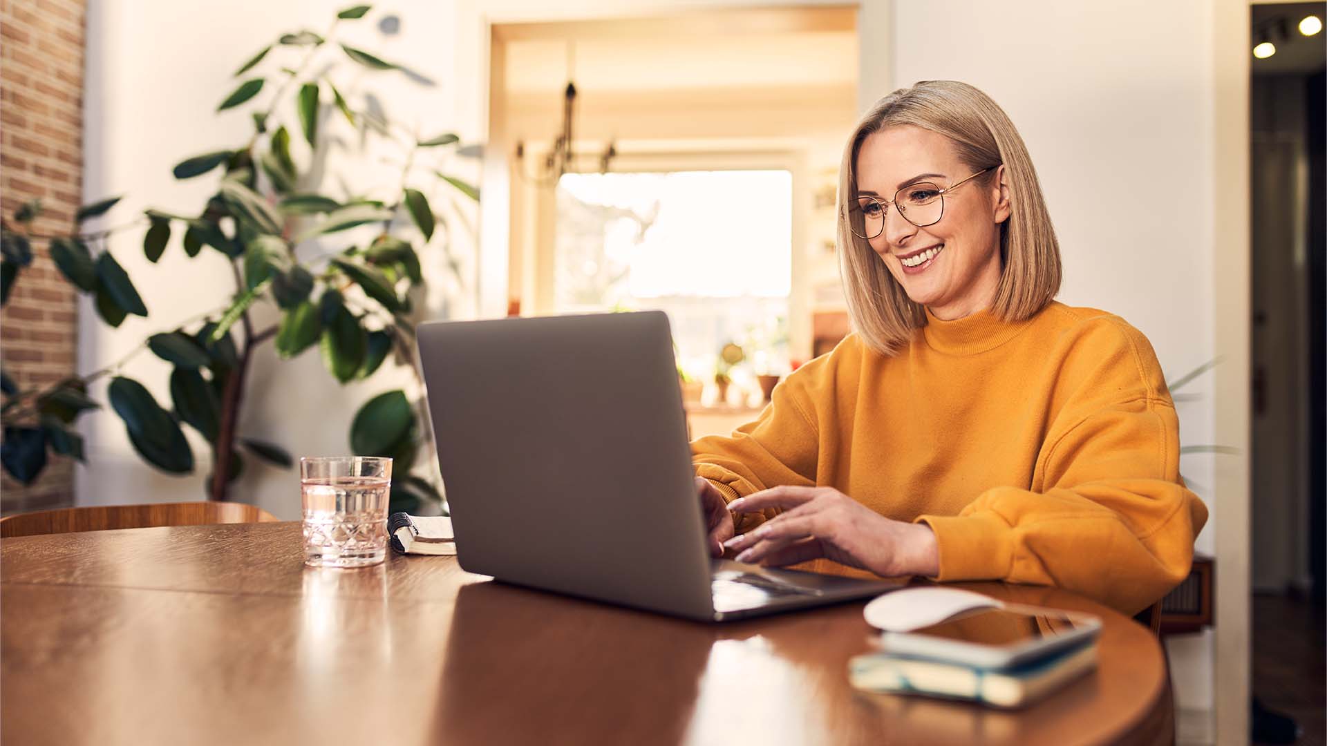 Eine Frau am Esstisch tätigt eine Überweisung an ihrem Laptop.