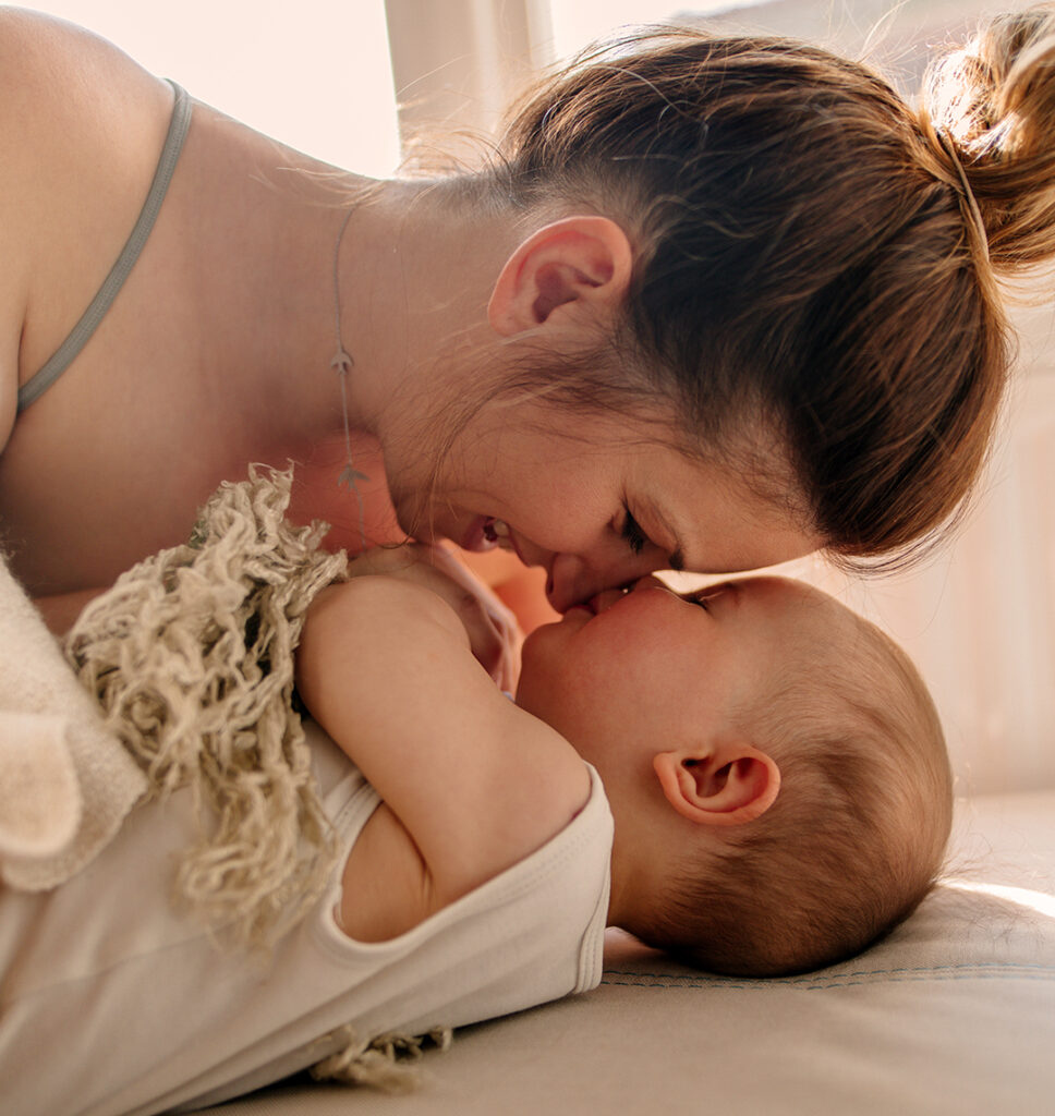 Eine Frau beugt sich über ihr Baby und lacht dabei.