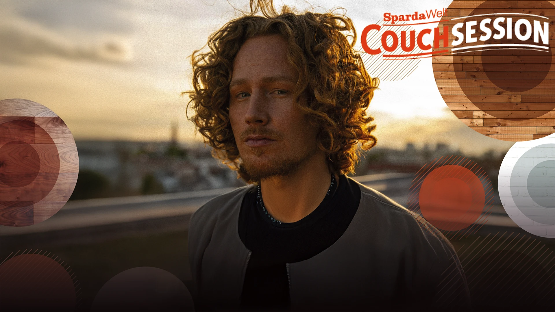 Michael Schulte steht vor einer Skyline und blickt leicht lächelnd in die Kamera.